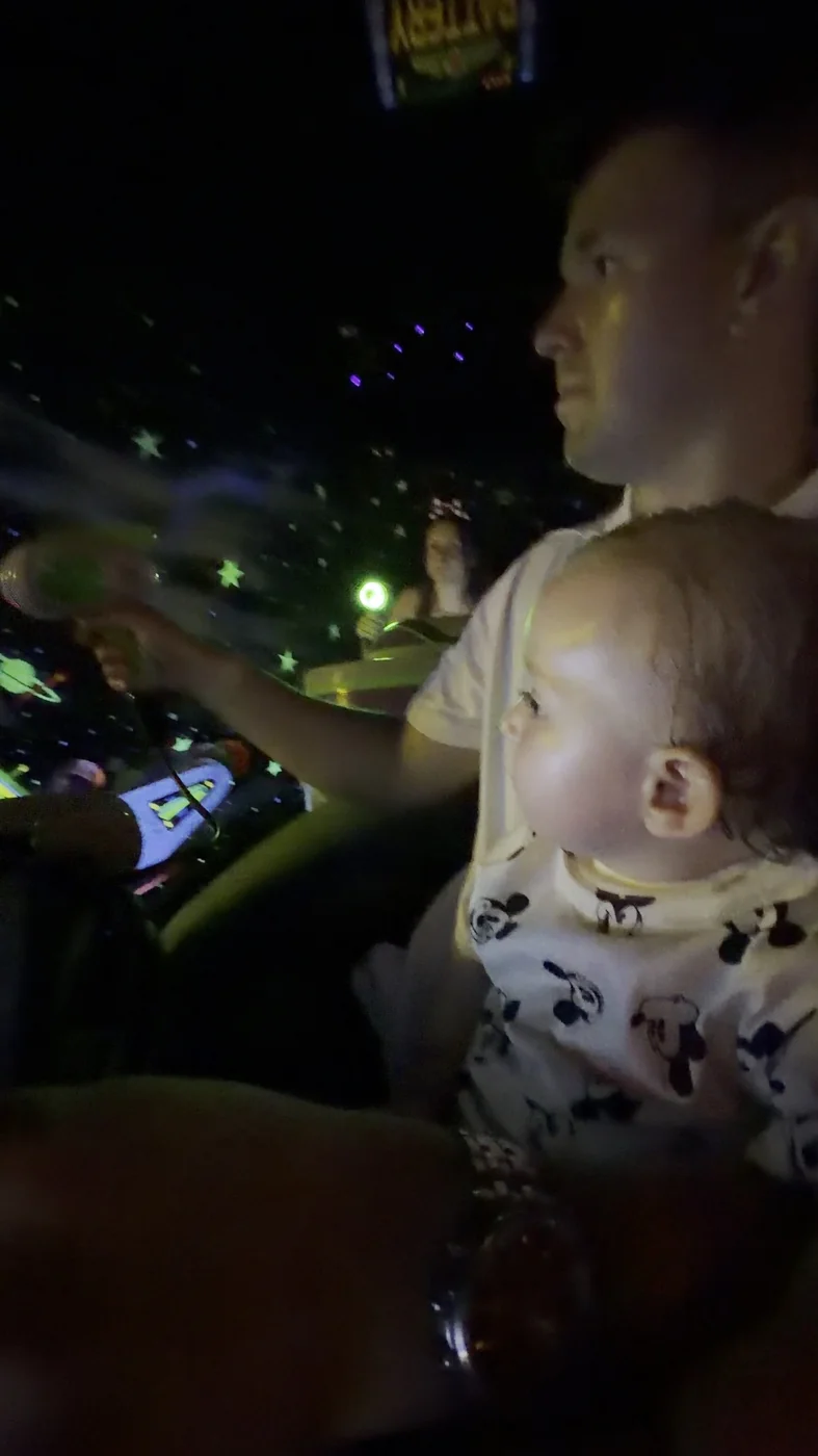 Adam holding George on his lap during Buzz Lightyear’s Space Ranger Spin, with the ride blaster visible