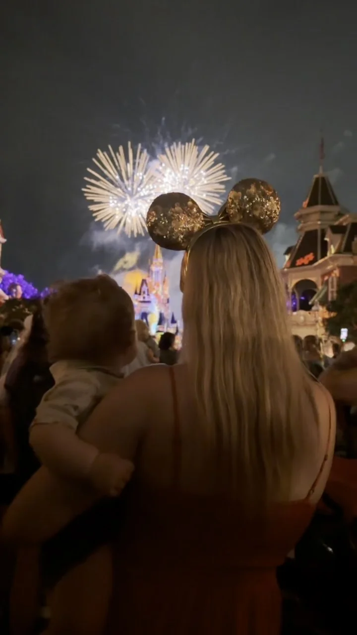 Jodie holding George as they watch fireworks above Cinderella Castle