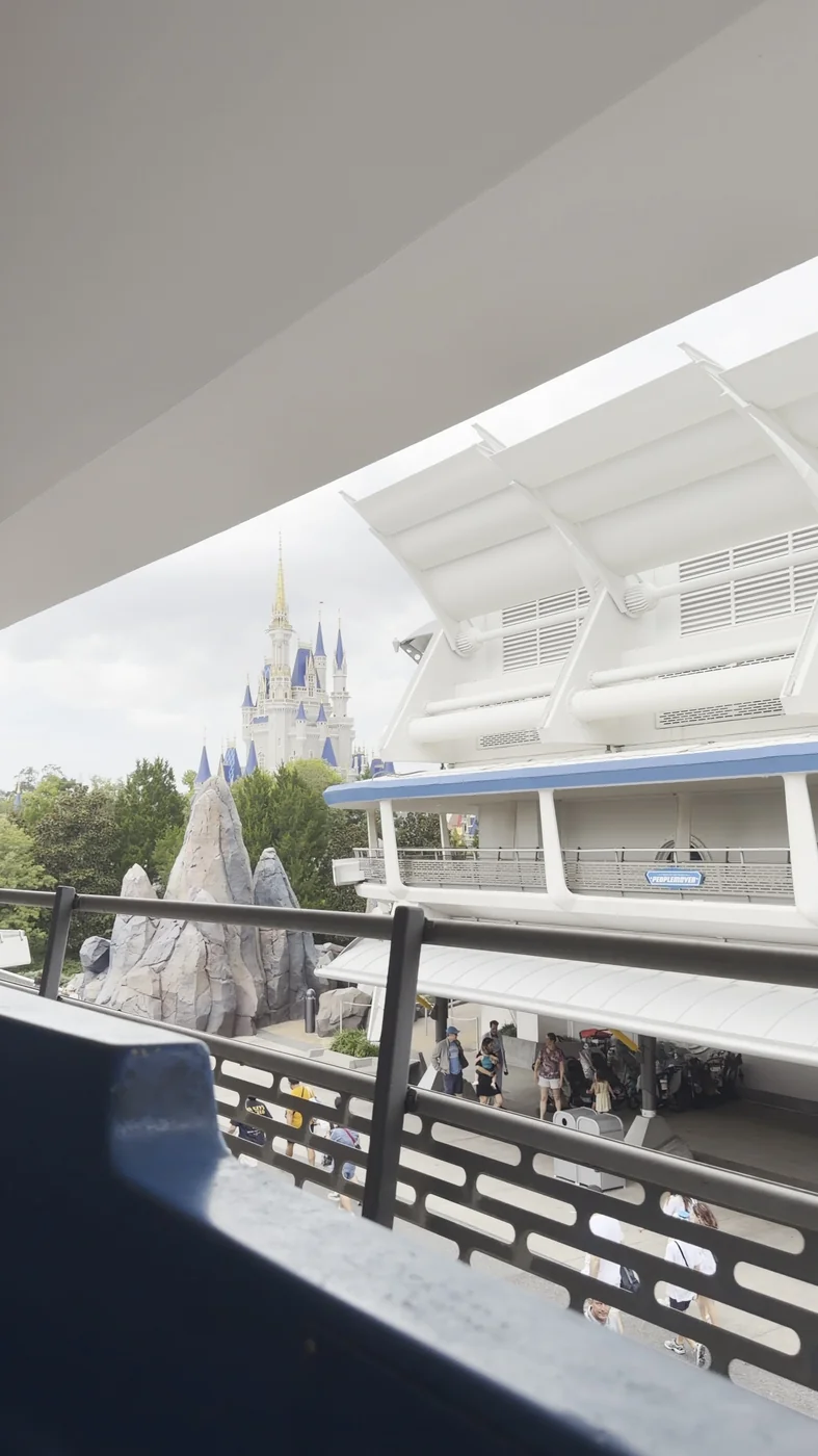Cinderella Castle and Tomorrowland seen from the PeopleMover, with the PeopleMover sign visible across the track