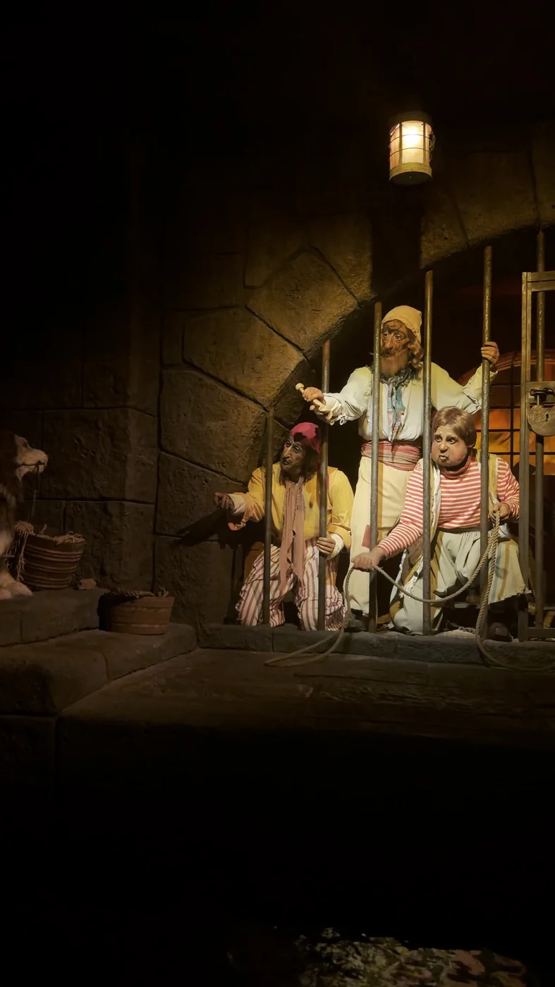 Pirate figures behind jail-cell bars beneath a lantern on Pirates of the Caribbean